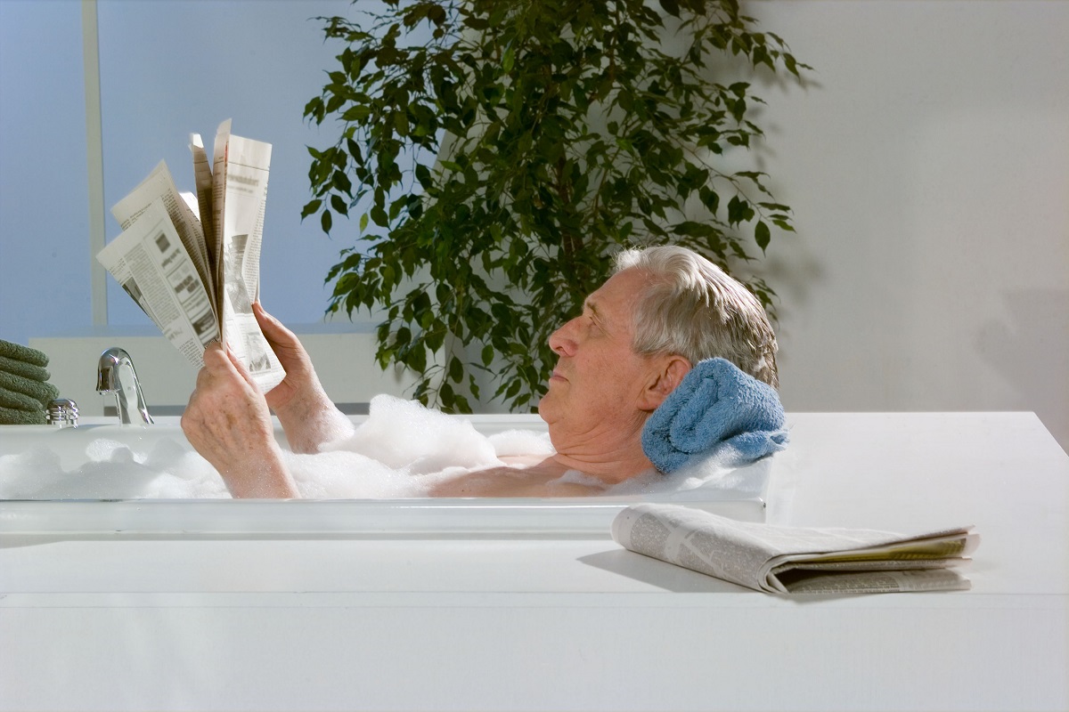 Man reading newspaper in bathtub