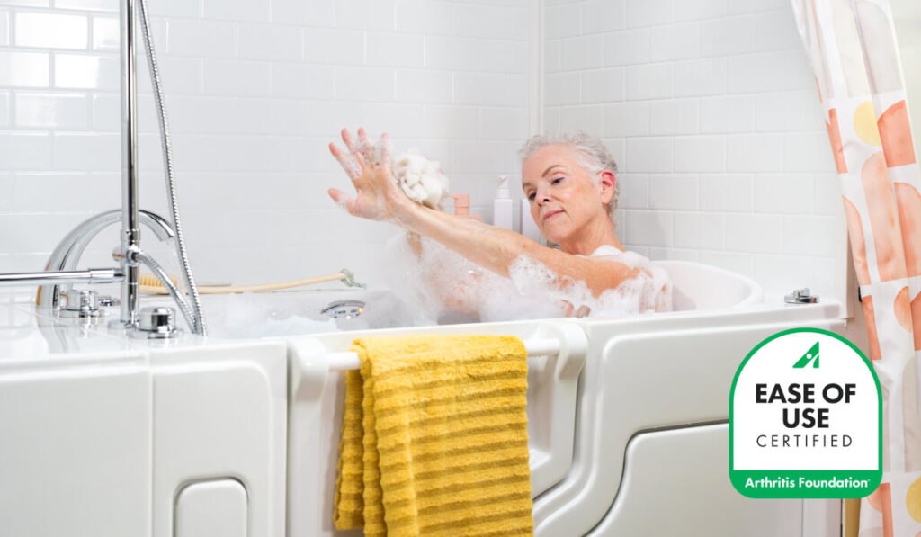 Woman washing arm in a walk-in tub. The Arthritis Foundation Ease of Use certification badge is in the corner of the image.