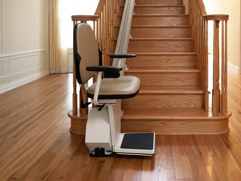 white indoor stairlift waiting at the bottom of a wood staircase