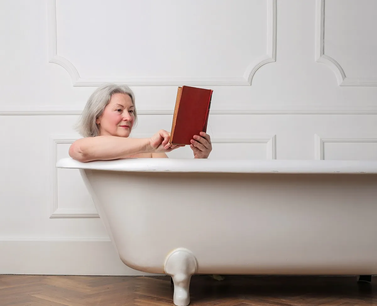 Elderly woman reading book in bath